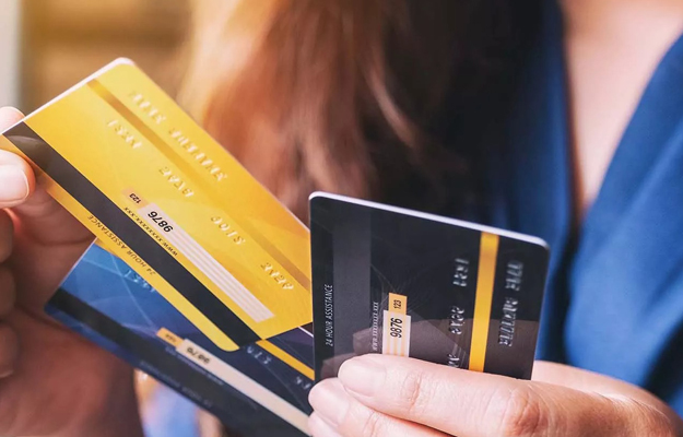 Person holding multiple credit cards in hand, displaying payment options.