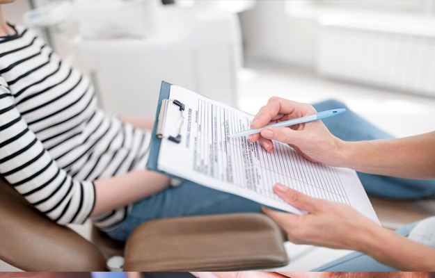 Patient signing dental consent form with dental professional at Sunridge Dental Care office.
