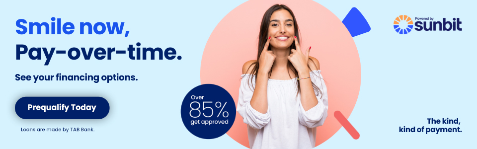 Woman smiling while holding credit card, promoting Sunbit dental financing options.