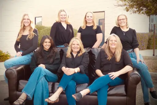 Sunridge Dental Care team of eight smiling dental professionals posing together indoors.