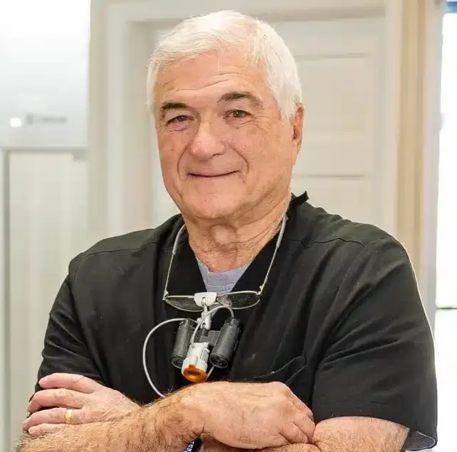 Dr. William smiles while wearing a black shirt and stethoscope in his Sun City West dental office.