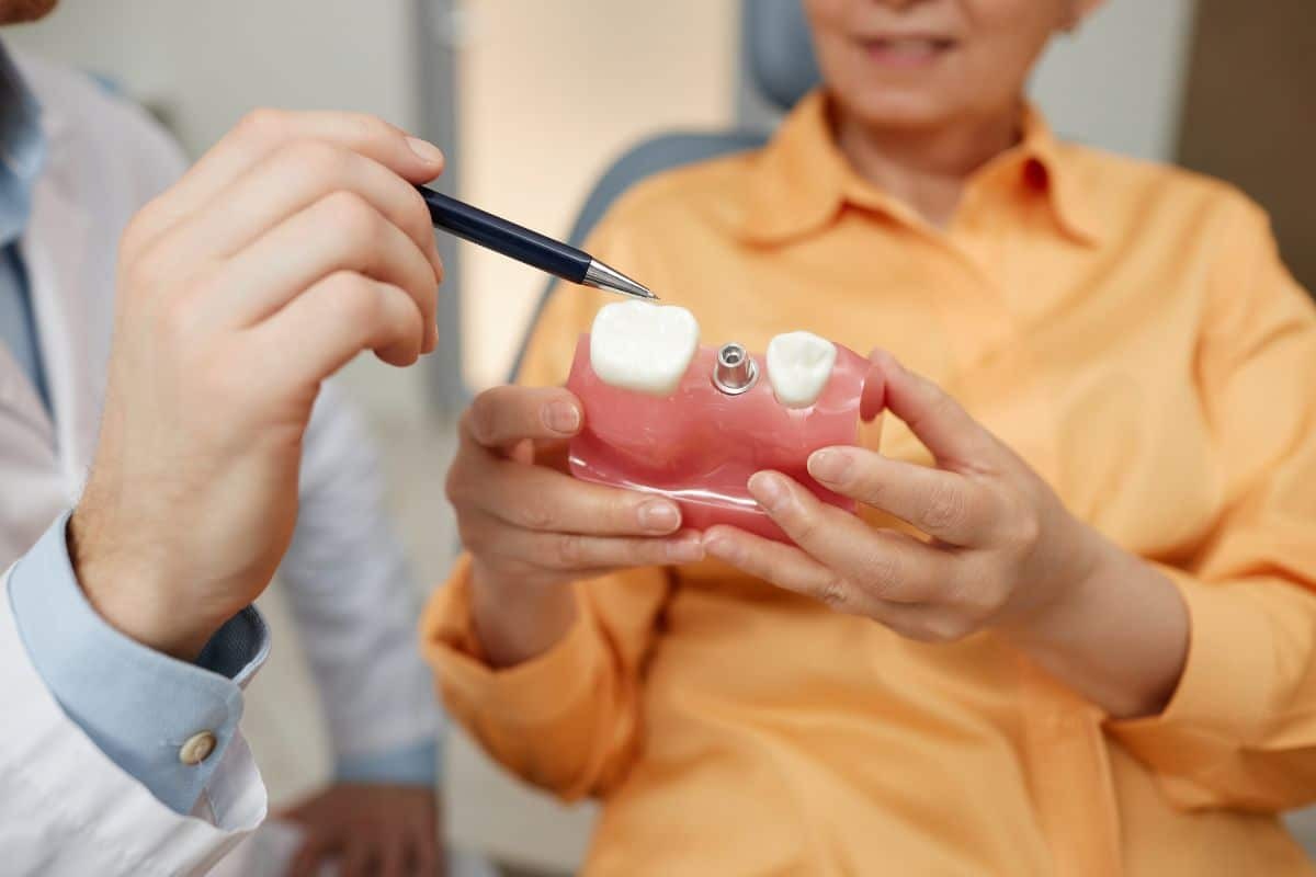 Dentist showing dental implant model with bone graft to patient in Sun City West.
